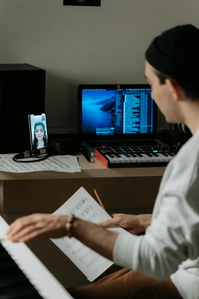 Musician engaged in a remote piano session with video call on phone.