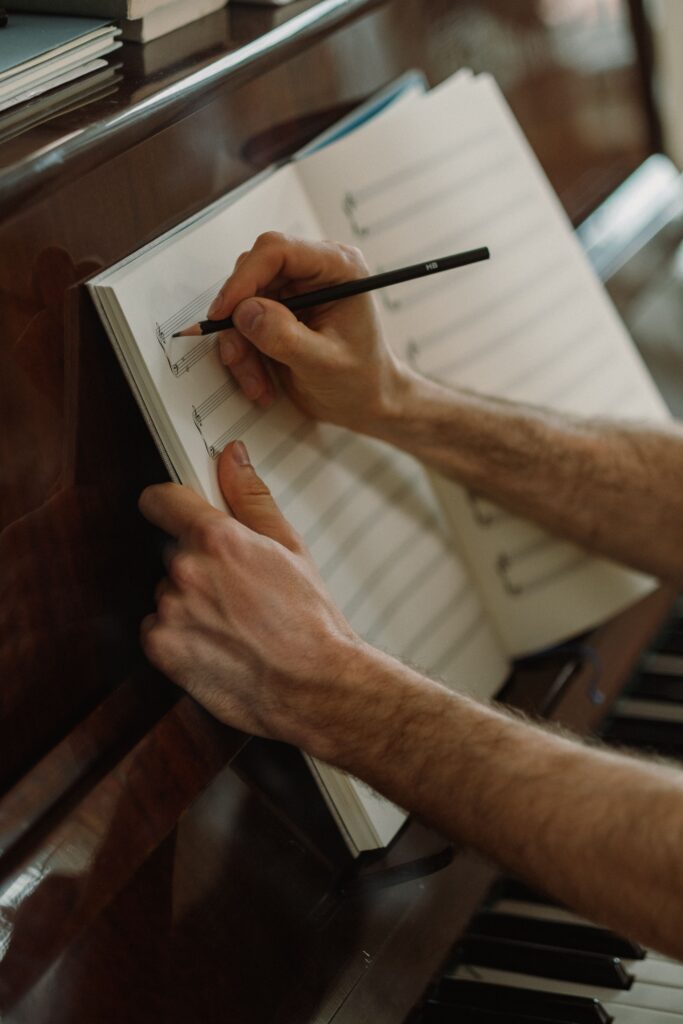 Why Music Theory Makes Learning Piano Easier A person composing music with pencil and sheet on a piano. Captures artistic creativity.